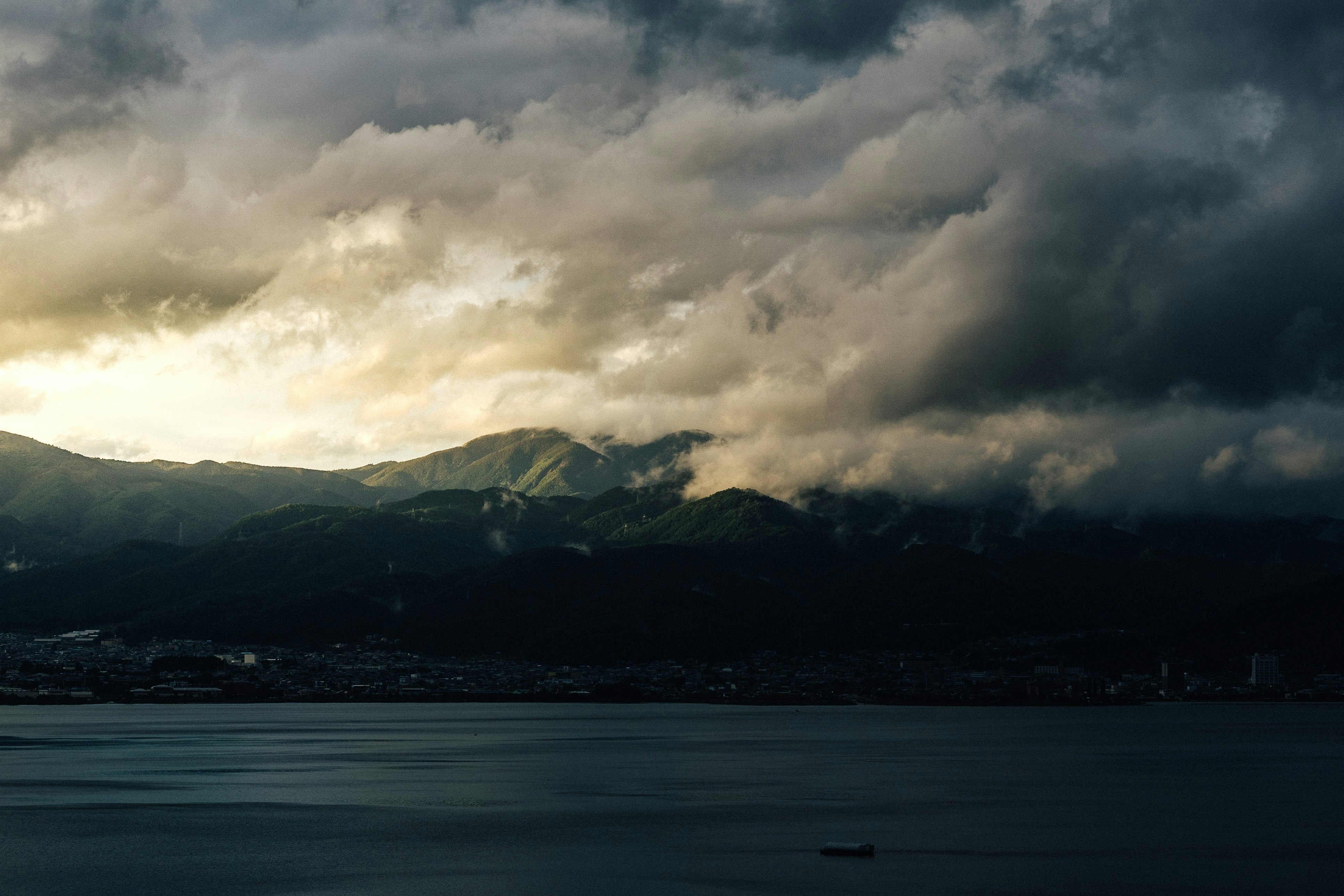 body of water near mountain under cloudy sky during daytime